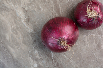 Two whole red onion bulbs on marble background