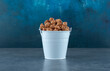 Blue bucket filled with popcorn candy on blue background
