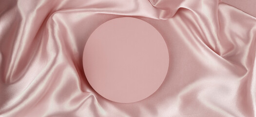 Wall Mural - Geometric round platform podium on pale pink silk satin background. Blank minimal cylinder form mock up background for cosmetic product presentation. Top view