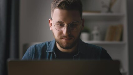Close up view of handsome bearded man typing on laptop, young coder writing code, home office with light interior