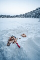 Poster - Vertical shot of a snowy field with chopped woods and an axe