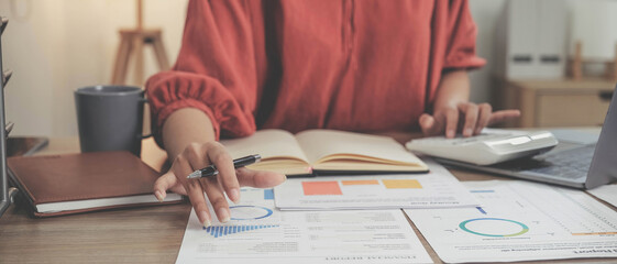 Business woman using calculator and laptop for do math finance on wooden desk in office and business working background, tax, accounting, statistics and analytic research concept