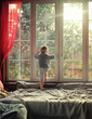 little boy looks out the window in a sunny room