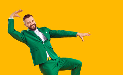 Wall Mural - funny man in a green suit dancing in the studio. portrait of a happy, cheerful guy wearing a green s