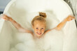 The girl bathes in a bath with white foam