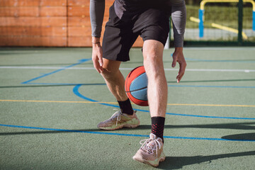 Young talent practices dribbling the basketball under his feet and improves his hand, body and foot coordination. Basketball game. Learning the trick, the deception