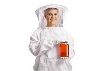 Wall Mural - Young female bee keeper in a uniform holding a jar of honey and smiling