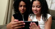 © Marco - Children using smartphone device at home, two girls looking at screen together