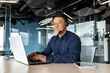 © Liubomir - Happy and smiling worker with headset for video call, Asian tech support man talking to online service users, businessman using laptop for online customer support.