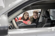 © MyJuly - man and a woman couple in a car dealership buy or trade in. car rental or repair service. happy and successful married couple choose a new car on credit. happy two people holding keys and laughing