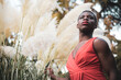A young black model poses in a red dress outdoors.Concept of androgynous man,LGTBI.