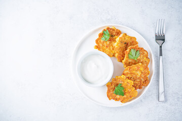 Wall Mural - Corn fritters in a plate with sour cream sauce