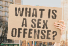 The Question " What Is A Sex Offense? " Is On A Banner In Men's Hands With Blurred Background. Assistant. Cruel. Dangerous. Despair. Employer. Horror. Job. Justice. Negative. Protect. Protection