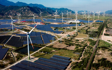 Solar panels and wind turbines generating alternative power and green renewable energy with blue sky background. Clean energy concept. Sustainable growth and climate change prevention.