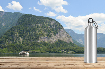 Wall Mural - Aluminum water bottle on wooden table and beautiful view of mountains, space for text