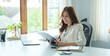 © wattana - Successful entrepreneur using laptop and working with accounting document at bright modern office.