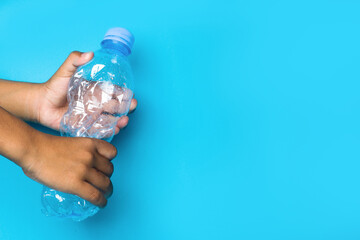  a child holding a trash bottle on blue background