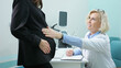 © lenblr - Confident doctor examines young pregnant woman in luxury clinic. Blonde therapist in white coat palpates belly of patient checking condition of foetus in office