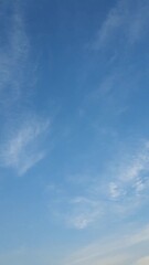 Wall Mural - Vertical shot of fast moving clouds in a clear blue sky in surise