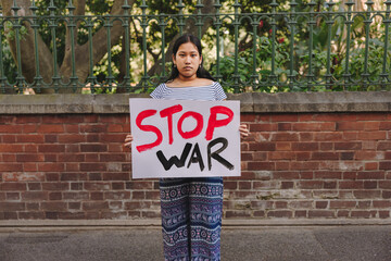 Wall Mural - Teenage girl holding an anti-war poster outdoors