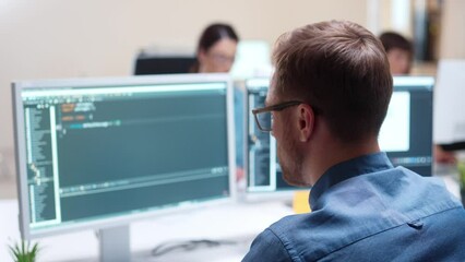 Close up. Rear of young Caucasian IT programer working on desktop computers typing on keyboard coding a program Professional worker writing website on sophisticated programming code language in office