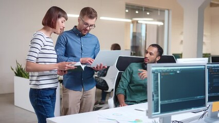 Wall Mural - team of young professional male and female it specialists work in office using laptop and computer d