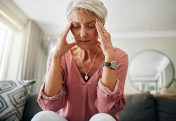 Headache pain, anxiety and senior woman thinking of mental health problem on the living room sofa in house. Sad elderly person with depression, home stress and frustrated with retirement on the couch