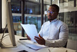 © N Lawrenson/peopleimages.com - Night worker, black businessman and paperwork planning, reading documents and financial reports at desktop computer in Jamaica. Young focus entrepreneur working expert strategy in dark modern office