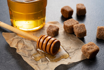 Wall Mural - Brown sugar with honey and wooden honey dipper on stone background.