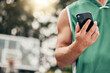 © C Coetzee/peopleimages.com - Man, hands and phone in sports communication and social media for basketball in the nature outdoors. Muscular male in sport fitness, exercise and game time check, message or text on mobile smartphone