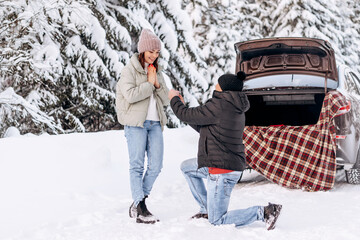 A young man in love offers his hand and heart to a young woman in a winter forest, gives a ring.Valentine's day,tenderness and love.