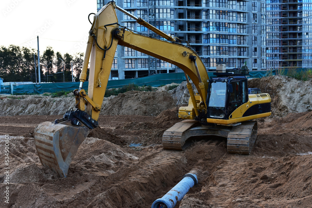 Sewage drainage system mounting at construction site. Excavator during laying sewer pipe and main systems. Civil infrastructure, water lines, sanitary sewers and storm sewers. Laying sewer pipes.