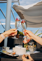 Two Women friends eating fresh oysters and drinking chilled prosecco wine on the summer sunset in restaurant. Seafood delicacies