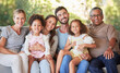 © Alex S/peopleimages.com - Portrait family, interracial smile and grandparents happy on living room sofa with children, smile together in lounge and relax on couch in house. Kids, mother and father with senior people for visit