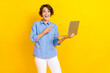 Portrait of impressed ecstatic girl with bob hairstyle wear blue blouse directing at laptop open mouth isolated on yellow color background