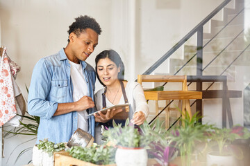 Coworkers using digital tablet at small business plant shop