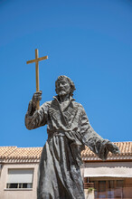 Statue Of A Spanish Religious Figure, Holding Aloft A Cross, Against A Deep Blue, Summer Sky