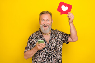 Photo portrait of nice grandparent hold device like heart notification wear trendy leopard print outfit isolated on yellow color background