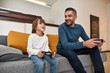 © Svitlana - Boy and father play video game on sofa at home