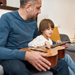 © Svitlana - Father teach son play notes on chords on guitar