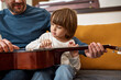 © Svitlana - Cropped dad teaching son play acoustic guitar