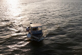 Fototapeta Las - A small fishing boat on the sea at sunset, elevated view.