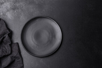 Empty black plate over dark stone background with free space. Top view