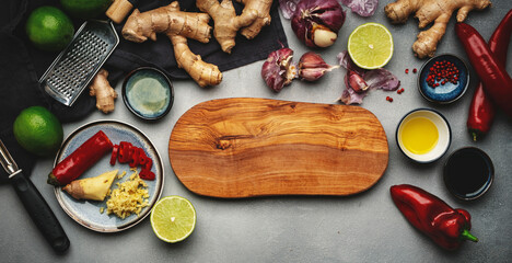 Asian cuisine ingredients, food background. Ginger, lime, chili pepper, garlic, soy sauce and rice vinegar and cutting board on gray kitchen table. Healthy eating concept. Top view