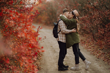 Happy couple in love newlyweds in casual clothes travel together, hike and walk in the autumn forest in nature.