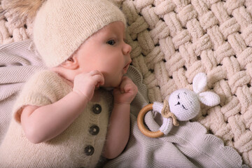 Wall Mural - Cute newborn baby with toy bunny on beige crocheted plaid, top view