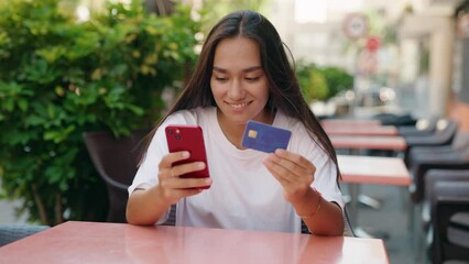 Sticker - Young beautiful hispanic woman using smartphone and credit card sitting on table at coffee shop terrace