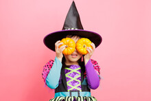 Happy Halloween! Young Girl With  Witch Costume And Hold  Small Pumpkins Against Plain  Background