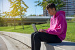 © pedro - Young man sits on step, using laptop and looks on his screen. Young man is blogging, chatting online,checking email. Student learning online. Sunny day. Lifestyle.