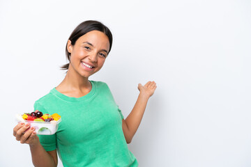 Wall Mural - Young hispanic woman holding a bowl of fruit isolated on white background extending hands to the side for inviting to come